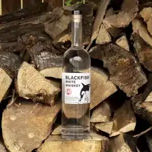 Bottle of White Whiskey on a Wood Pile